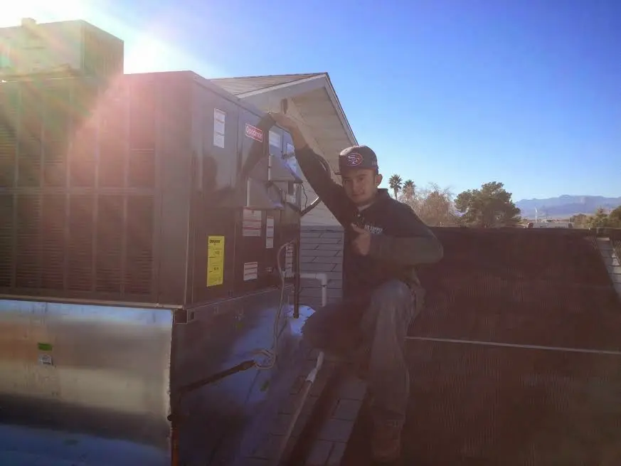 HVAC technician performing Air Duct Cleaning on a rooftop unit in Midway